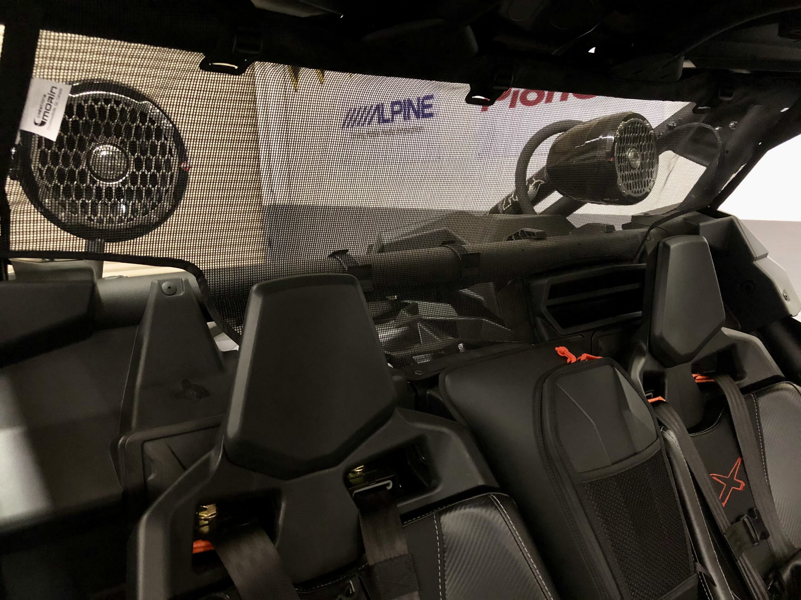Water-resistant speaker pods mounted on rear roll cage bar of side-by-side